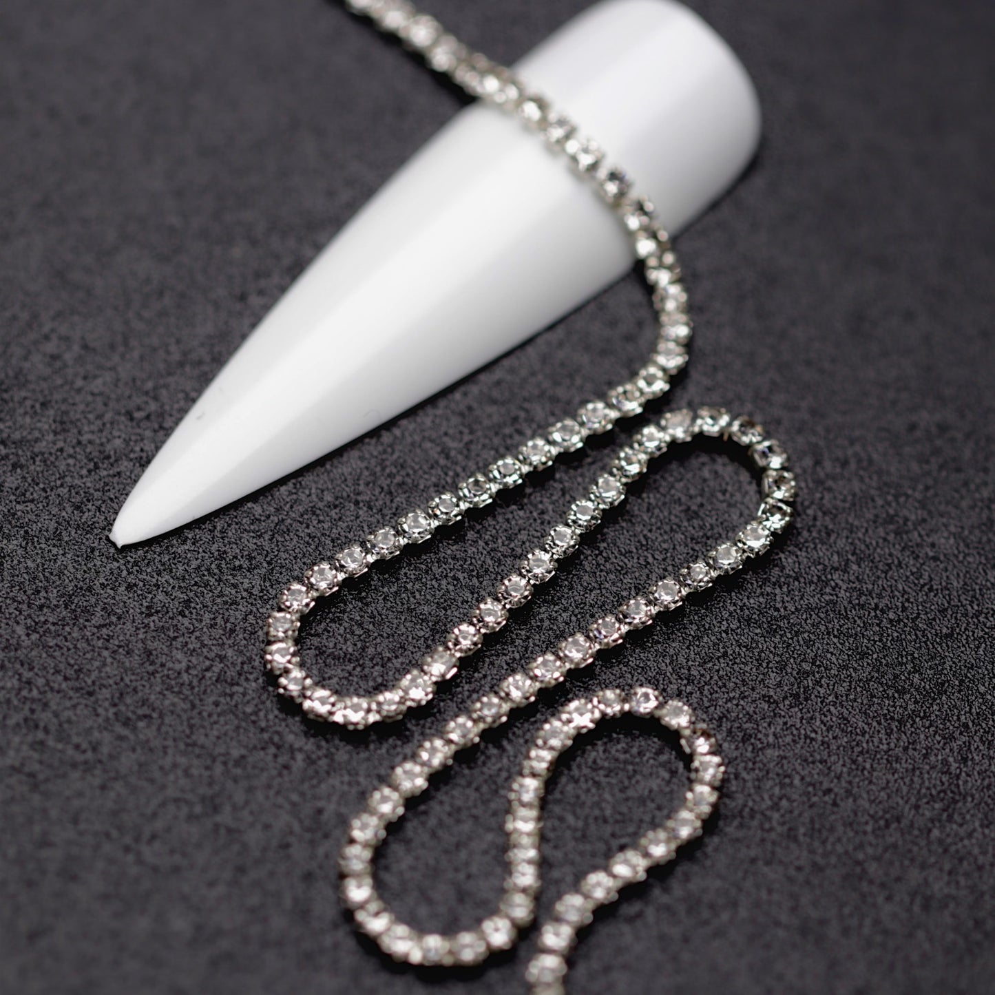 Close-up of silver 1.5 mm clear crystal rhinestone cup chain for nail art on black background