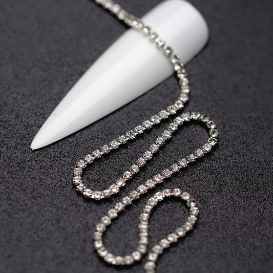 Close-up of silver 1.5 mm clear crystal rhinestone cup chain for nail art on black background