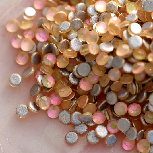 Scattered Cream Pie flatback glass rhinestones showing soft beige-gold tones foil backing and subtle rainbow highlights for crafts and manicures