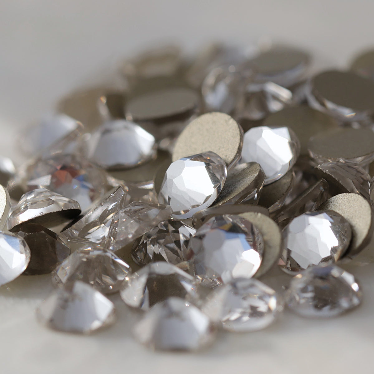 Clear flatback rhinestones with a 16-facet (8+8) cut and metallic foil backs forming a sparkling pile.