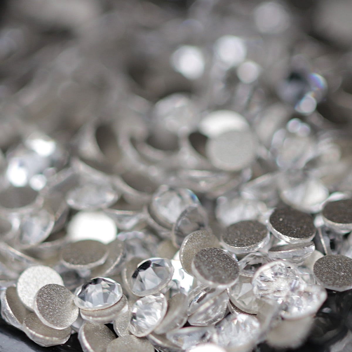 Clear Flatback K9 Crystal rhinestones with faceted tops and metallic foil backs scattered in a sparkling pile.