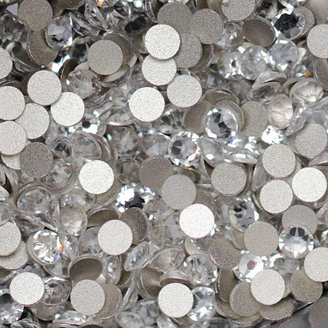 Clear Flatback K9 Crystal rhinestones with faceted tops and metallic foil backs scattered in a sparkling pile.
