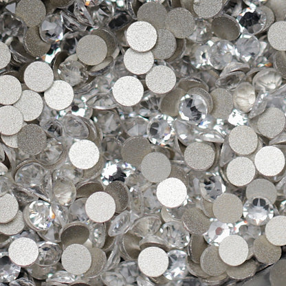 Clear Flatback K9 Crystal rhinestones with faceted tops and metallic foil backs scattered in a sparkling pile.