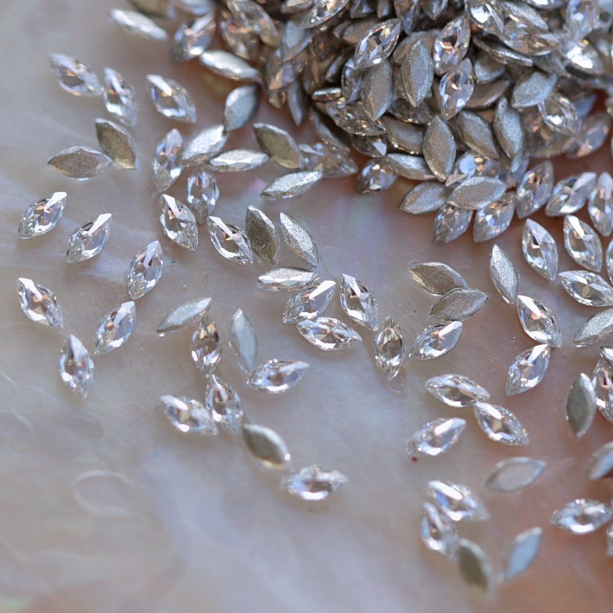 Close-up of sparkling clear marquise-shaped flatback zircon crystals with silver backs, perfect for creating elegant nail designs and crystal patterns