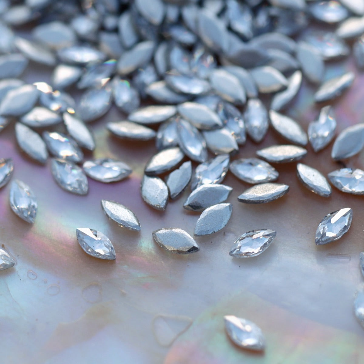 Close-up of sparkling clear marquise-shaped flatback zircon crystals with silver backs, perfect for creating elegant nail designs and crystal patterns