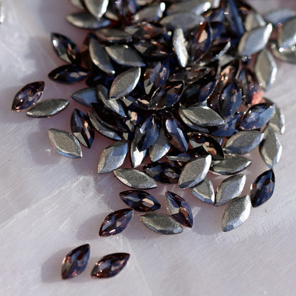 Scattered Damson color marquise crystals with grayish-lilac metallic facets and high reflectivity for nail decoration