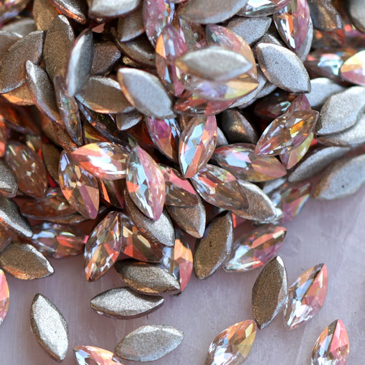 Close-up of Flatback Zircon Marquise Copper AB rhinestones, highlighting the faceted navette shape and glowing peach-gold iridescent finish used for creative nail designs.