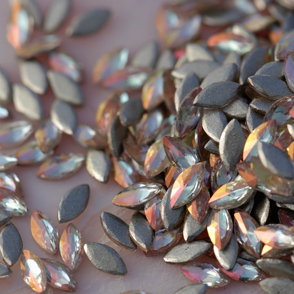 Close-up of Flatback Zircon Marquise Copper AB rhinestones, highlighting the faceted navette shape and glowing peach-gold iridescent finish used for creative nail designs.