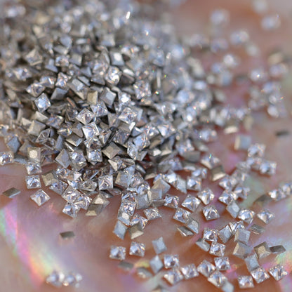 Clear flatback zircon square crystals scattered on an iridescent background, showing tiny geometric stones ideal for precise nail art designs