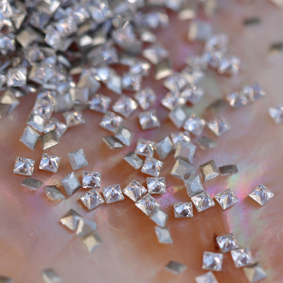 Close-up of sparkling clear square-shaped flatback zircon crystals with metallic silver backs, perfect for creating modern, grid-style nail art and embellishments