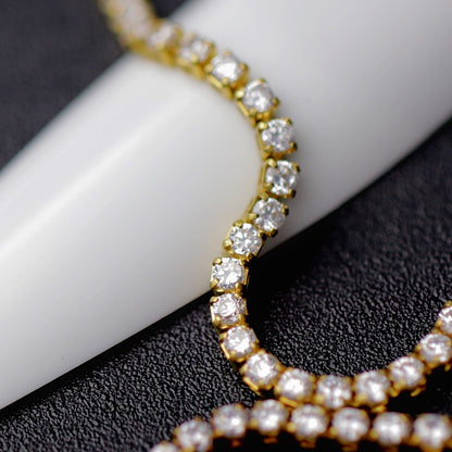 Gold 1.2 mm clear zirconia rhinestone nail art chain wrapped around a white nail tip on a black background