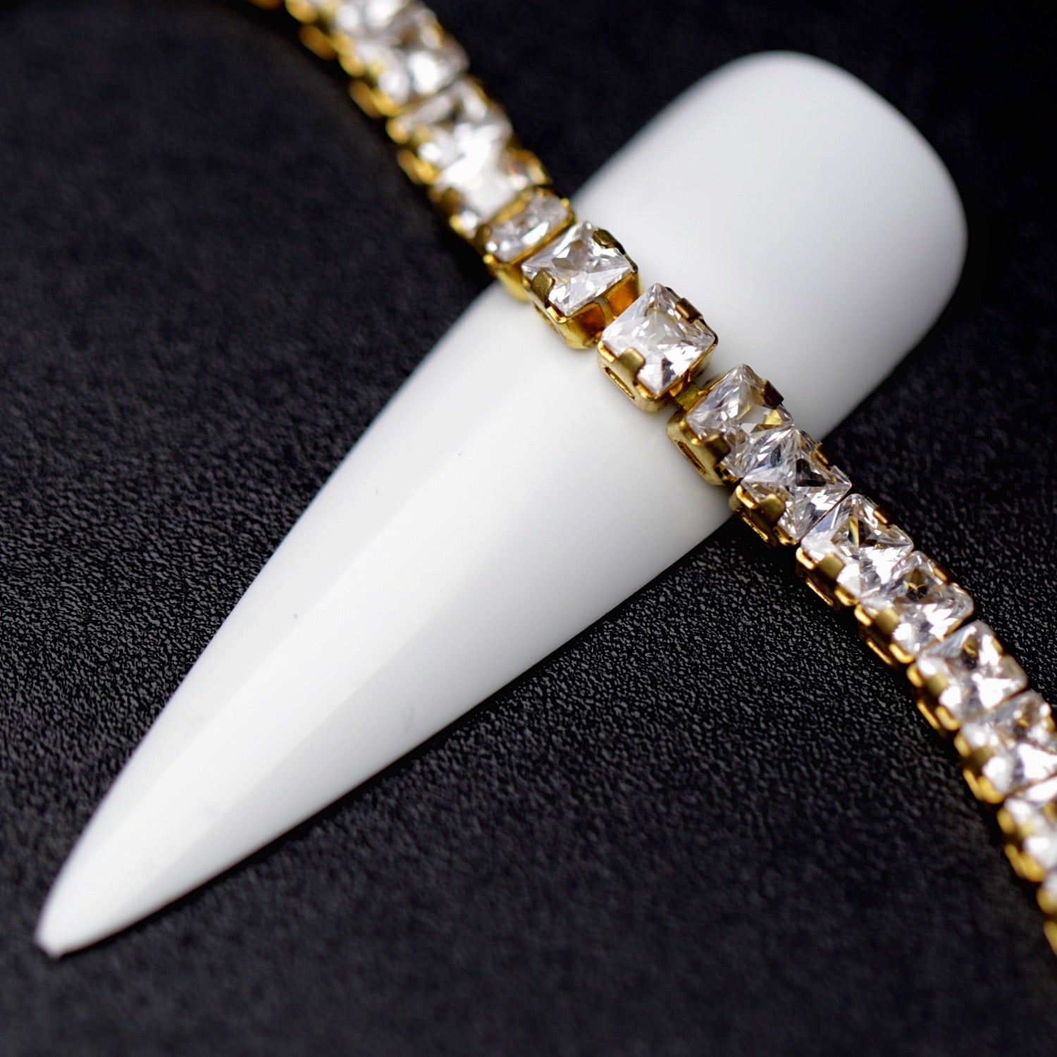 Gold 3×3 mm clear zirconia square rhinestone nail art chain displayed around a white nail tip on a black background