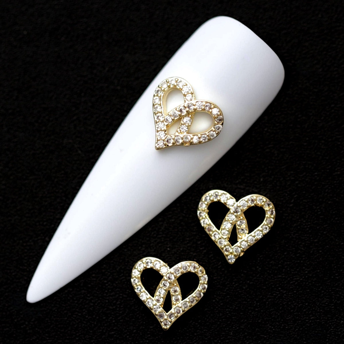 Gold 10×9 mm open heart nail charm with mini crystal CZ stones displayed on a white nail tip and black background
