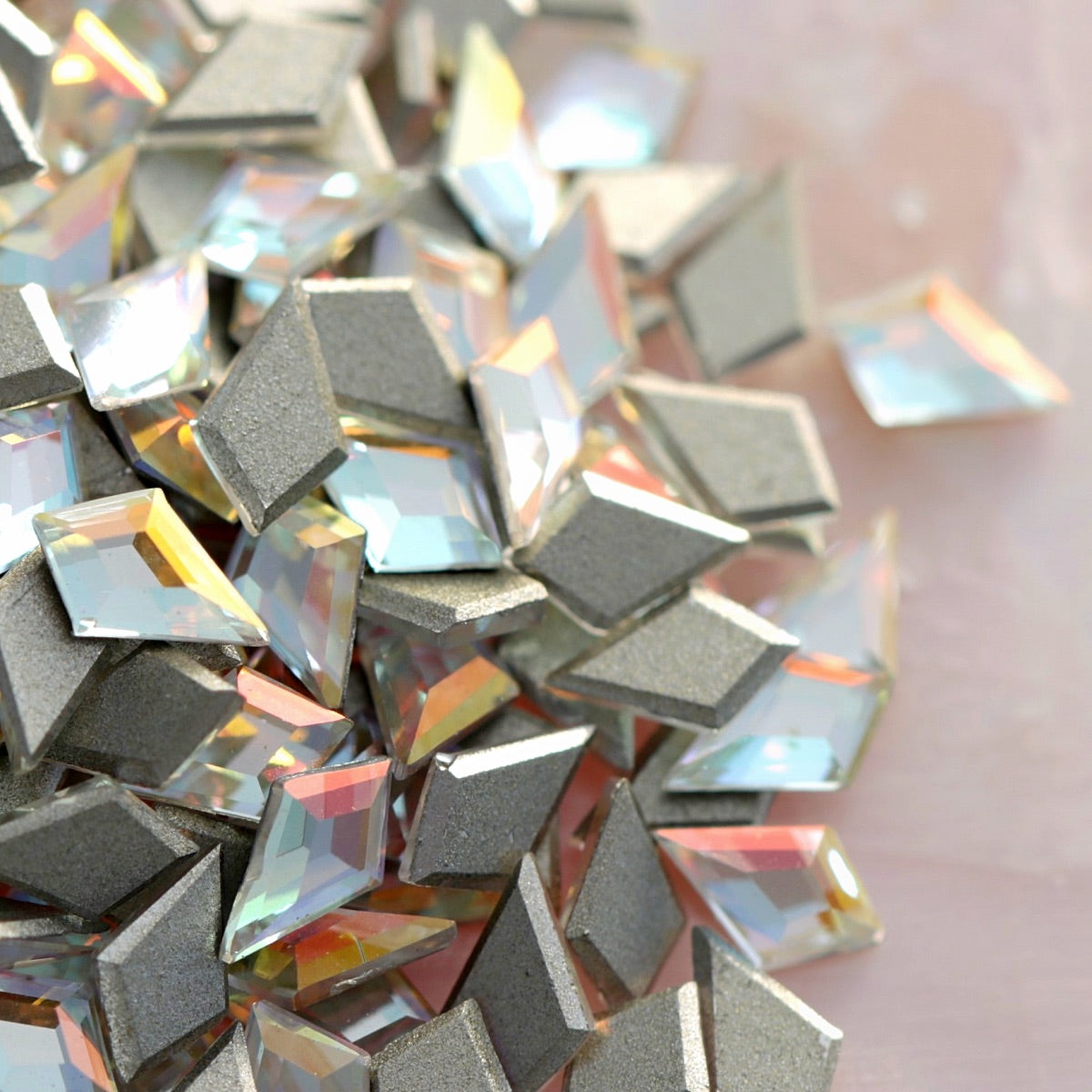 Close group of iridescent Crystal Gold Shimmer K9 flatback deltoid crystals highlighting multi-color light play and metallic silver backing for luxury crafts