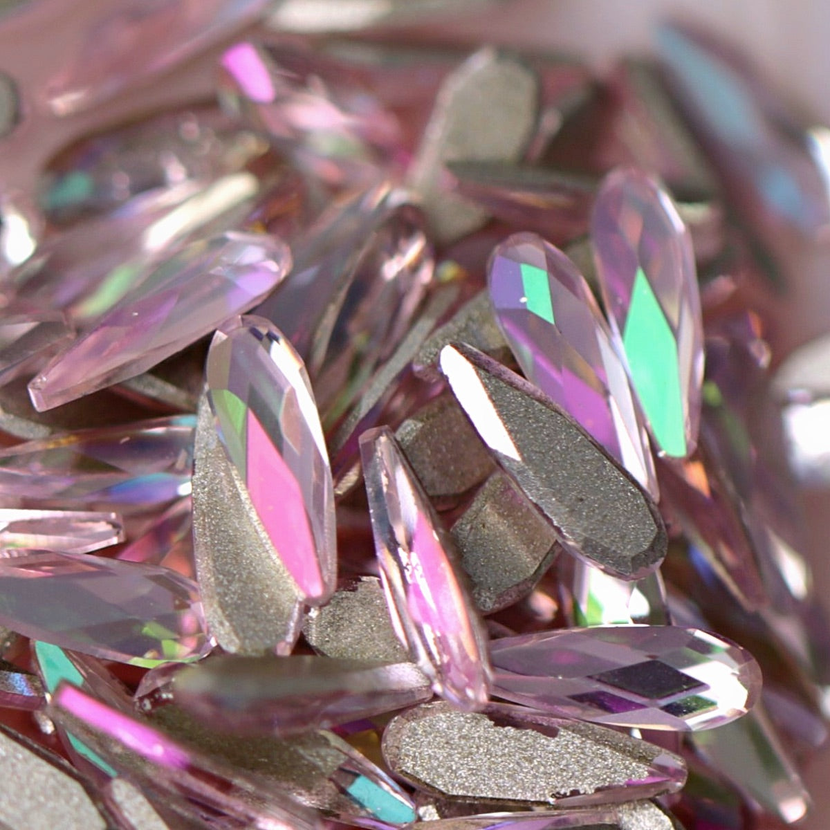 Close-up of K9 Crystal Flatback Raindrop Luminous Light Rose crystals, highlighting the delicate pink color and high-shine raindrop shape ideal for elegant manicures.