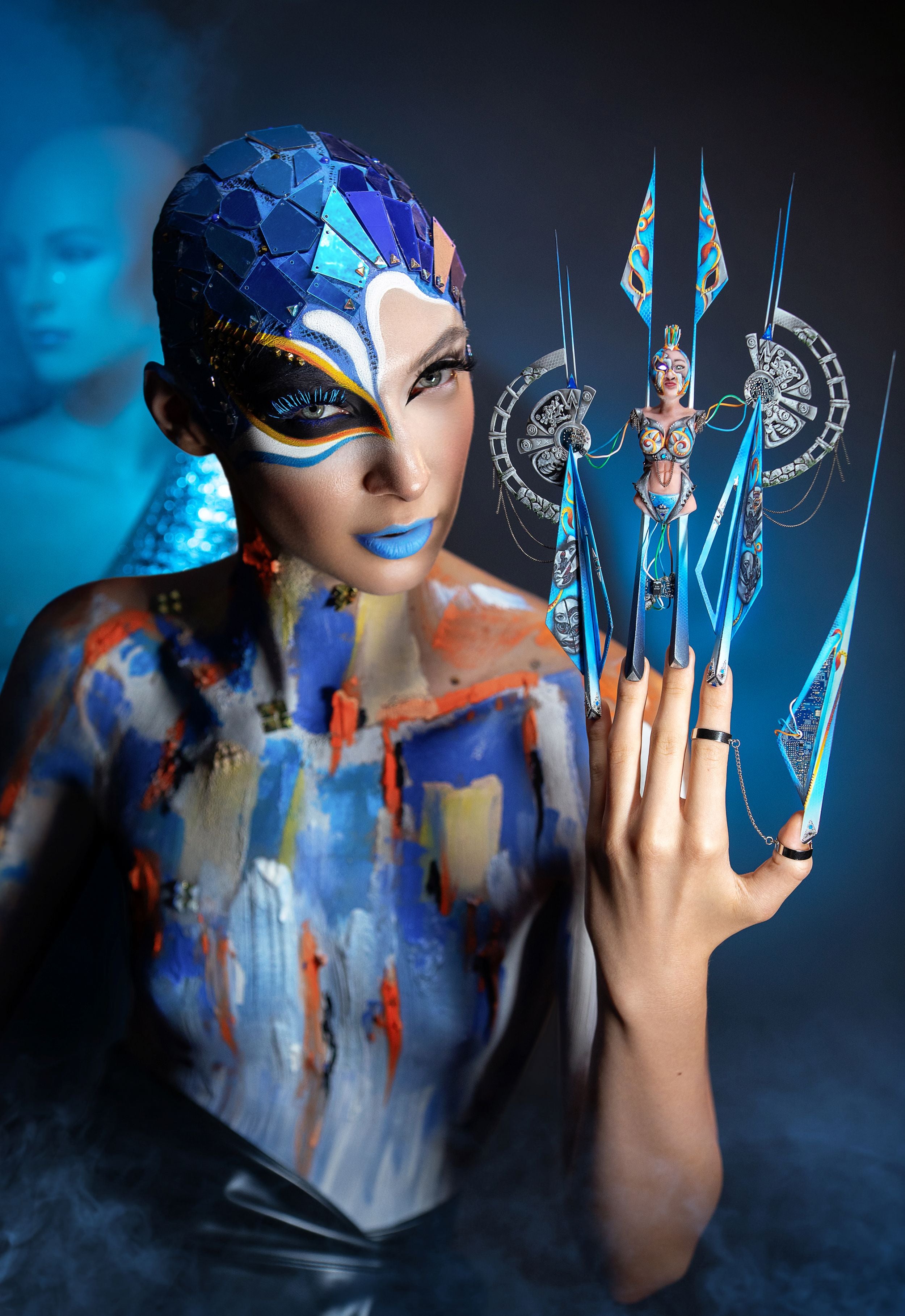 Model with avant-garde blue and orange makeup and highly detailed competition nail design, illustrating the advanced nail art techniques and crystal decoration ideas featured in the Eunails blog