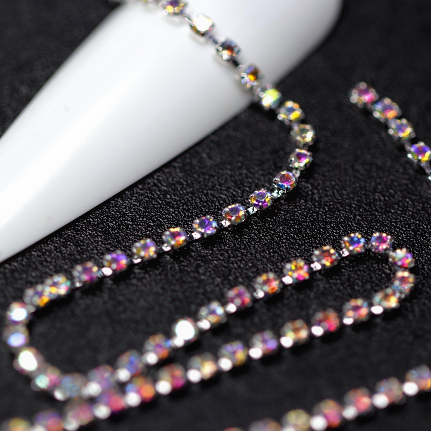 Close-up of silver 1.5 mm Crystal AB rhinestone cup chain for nail art on black background