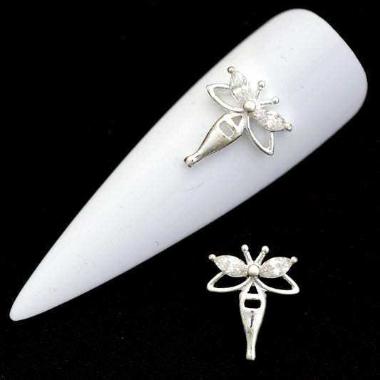 Silver fairy nail charms with marquise crystal CZ wings and a small round crystal accent on a white nail tip against a black background.