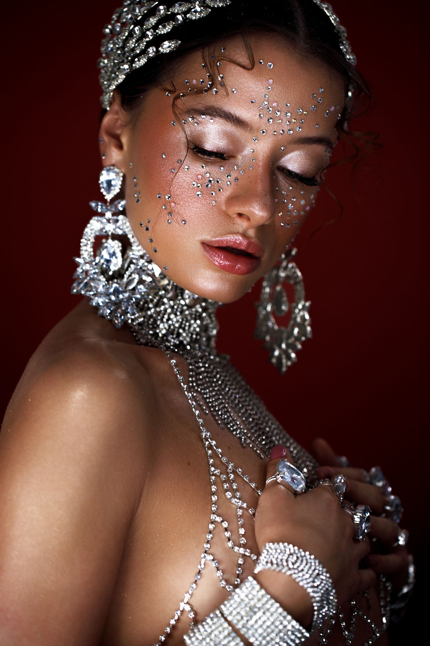 Close-up of a woman wearing dramatic crystal necklace, earrings and hand jewelry, symbolizing the luxurious nail art and design possibilities offered by Eunails