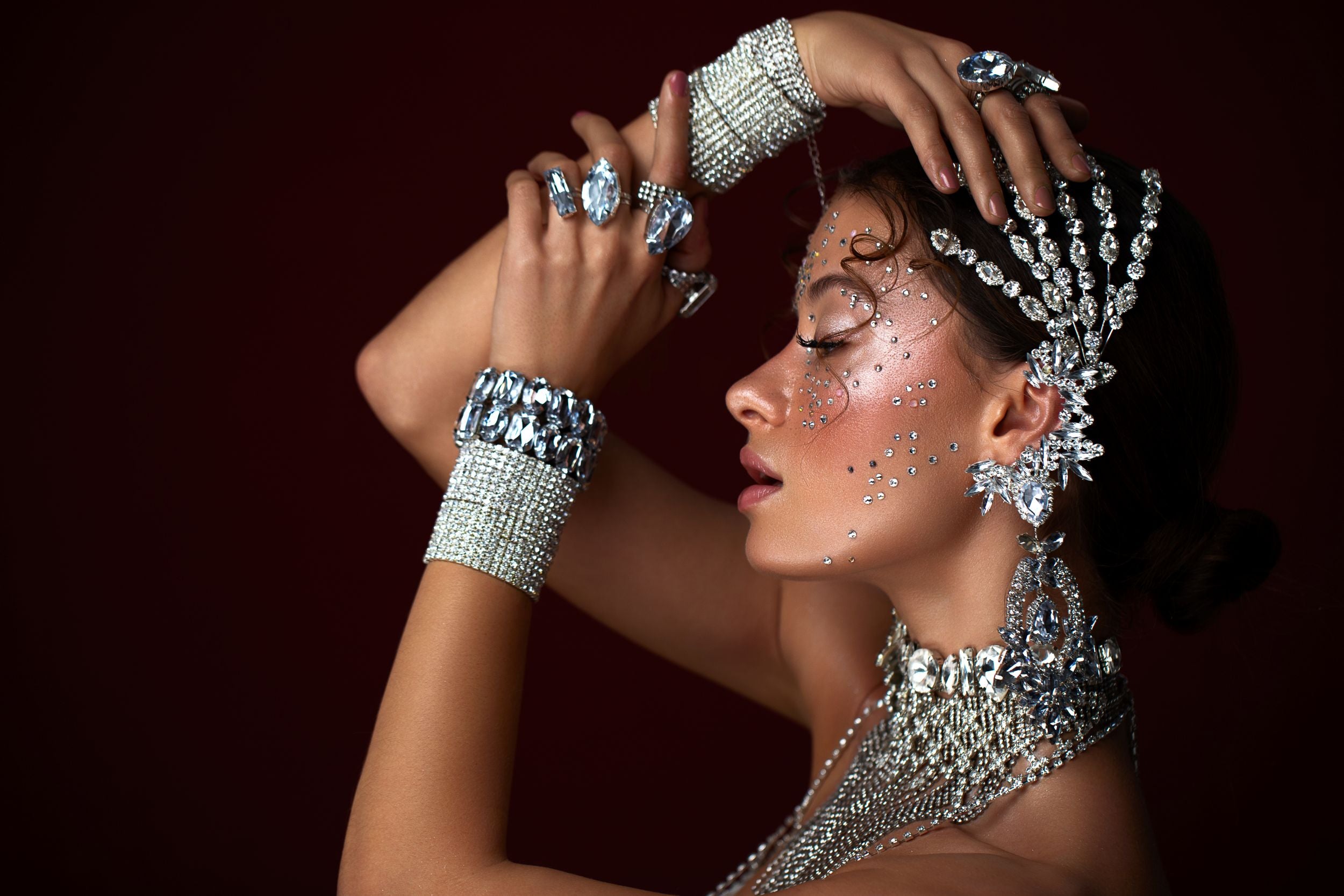 Detailed view of hands and head adorned with large clear crystals, representing the designers, performers and artists Eunails serves with premium rhinestones and embellishments